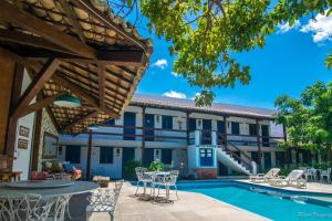 a resort with a pool and chairs and a building at Pousada Sao Luiz in Porto Seguro