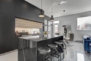 a kitchen with black cabinets and bar stools at Les Lofts du Centre by Simplissimmo in Montréal