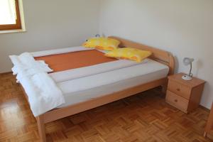 a bed with yellow and orange pillows on it at Apartma Ana in Bavšica