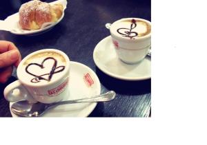 deux tasses de café avec des coeurs peints sur une table dans l'établissement Little Rose Rooms, à Rome