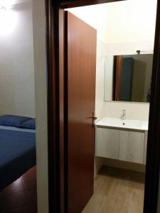 La salle de bains est pourvue d'un lavabo et d'une porte avec un miroir. dans l'établissement Honey House Parma, à Parme