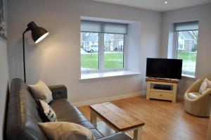 a living room with a couch and a flat screen tv at Beehive Cottage in Ellon