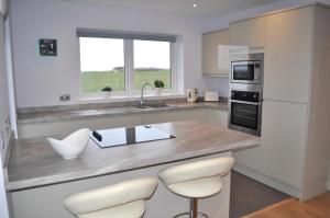 a kitchen with a counter with chairs and a sink at Beehive Cottage in Ellon