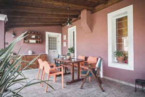 a dining room with pink walls and a table and chairs at Birdsing Cottage in Dassia
