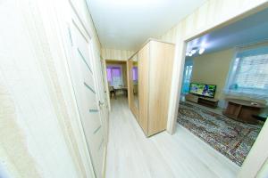 einen Flur, der zu einem Wohnzimmer mit einem Spiegel führt in der Unterkunft Apart on Slavskogo 14 in Öskemen