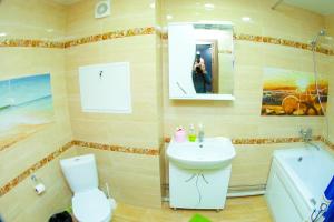 a bathroom with a sink and a toilet and a mirror at ApartLux on Slavskogo 26 View River in Ustʼ-Kamenogorsk