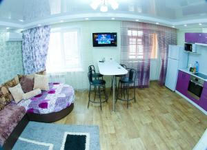 ein Wohnzimmer mit einem Bett und einem Tisch sowie eine Küche in der Unterkunft ApartLux on Republic Square in Öskemen