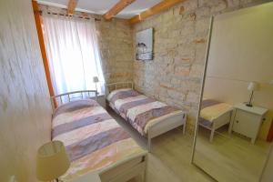 1 dormitorio con 2 camas y pared de piedra en Villa Giardin, en Novigrad Istria