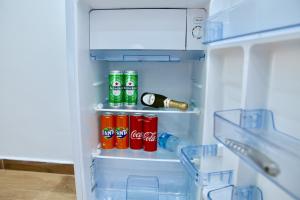 an open refrigerator with soda cans and a bottle of cocacola at Andolfi 24 Rooms in Pompei