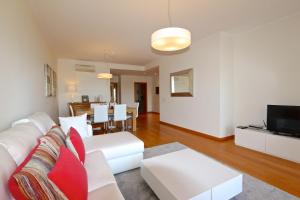 uma sala de estar com um sofá branco e uma televisão em Golf Mar Village - Clever Details em Vilamoura