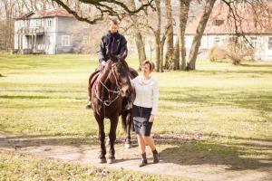 a woman standing next to a man riding a horse at Pālena apartamenti in Tērvete