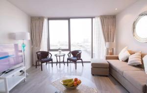 a living room with a couch and a tv at Mayfair Serviced Apartment - D1 Tower in Dubai