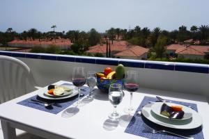 una mesa con copas de vino y un bol de fruta en Taidia Sunset View, en Playa del Inglés