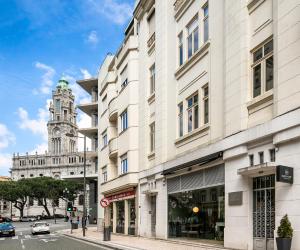 a building on a city street with a clock tower at ALQUIMIA DOS ALIADOS - Gorgeous Palace Apartment in Porto