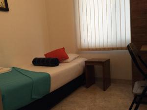 1 dormitorio con cama con almohada roja y ventana en The Palma Home, en Bogotá