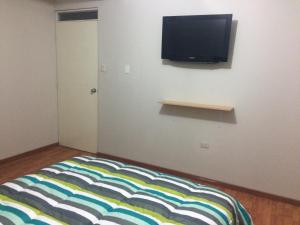 a room with a bed with a television on a wall at Hospedaje de los Reyes in Huarmey