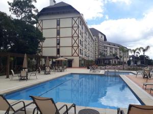 a pool at a hotel with chairs and a building at Loft luxo em Pedra Azul in Pedra Azul