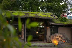 a building with a moss covered roof with a rock at Yunosato Hayama in Beppu