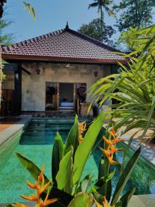 a villa with a swimming pool in front of a house at Taman Senang in Gili Islands
