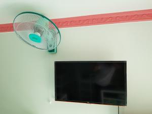 a fan hanging on a wall next to a tv at Minh Kim Guesthouse in Ấp Phó