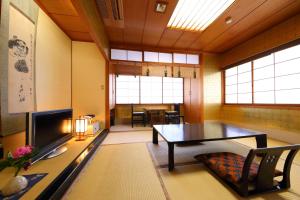 ein Wohnzimmer mit einem Tisch und einem TV in der Unterkunft Onyado Takasago in Ureshino