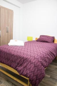 a bed with a purple comforter in a room at Cuzco Apartment in Cusco