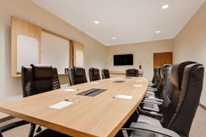 Microtel Inn & Suites by Wyndham Clarion في كلاريون: قاعة اجتماعات مع طاولة وكراسي خشبية كبيرة