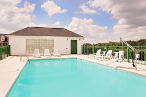 a swimming pool with chairs and a house at Days Inn by Wyndham Spartanburg in Spartanburg