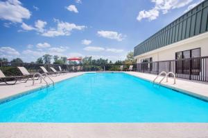 a swimming pool with chairs and a building at Days Inn by Wyndham Metter in Metter