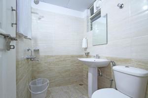 a bathroom with a white toilet and a sink at Arra Suites kempegowda Airport Hotel in Devanhalli +25 photos