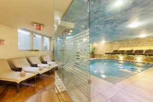 Habitación con piscina con bancos y pared de cristal. en Hotel Leitner, en Rio di Pusteria