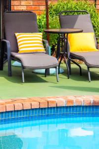- deux chaises et une table à côté de la piscine dans l'établissement Crescent Motel Taree, à Taree