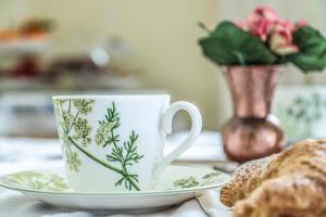 een kopje koffie en schotel met een vaas met bloemen bij Scognamiglio Suites in Ercolano