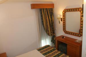 a small room with a mirror and a bed at Real Caparica Hotel in Costa da Caparica