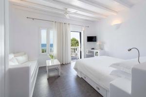 a white bedroom with a bed and a balcony at Nefeli Sunset Studios in Pollonia