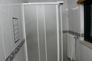 a bathroom with a glass shower door with towels at Real Caparica Hotel in Costa da Caparica
