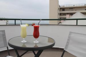 two cocktails sitting on a table on a balcony at Real Caparica Hotel in Costa da Caparica
