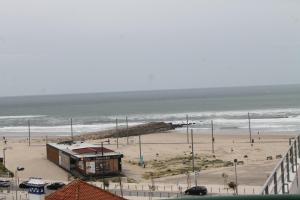 a view of a beach with a building and the ocean at Real Caparica Hotel in Costa da Caparica