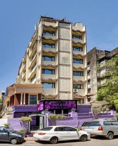 ein hohes Gebäude mit davor geparkt in der Unterkunft Ramee Guestline Hotel Khar in Mumbai