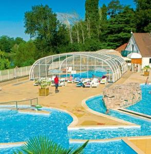una piscina con 2 piscinas y una casa de cristal en Mareva37, en Trogues