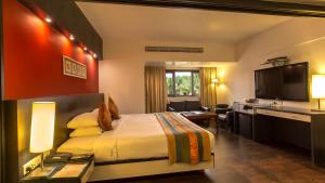 a hotel room with a bed and a flat screen tv at Ramee Guestline Hotel Khar in Mumbai