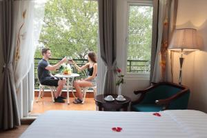 a man and woman sitting at a table in a hotel room at Hanoi Siva Luxury Hotel & Travel in Hanoi