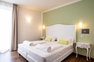a bedroom with a white bed with two green pillows at Hotel Speranza in Bardolino