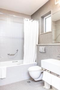 a white toilet sitting next to a bath tub in a bathroom at The Lansdowne Hotel in Dublin
