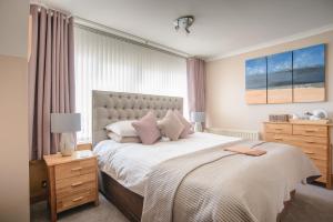 a bedroom with a large bed with pink pillows at Jannel Bed & Breakfast in Stornoway