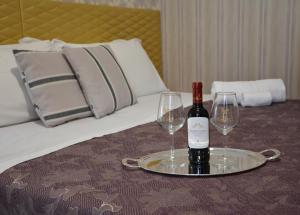 a tray with a bottle of wine and two glasses on a bed at Le Stanze del Console in Gravina in Puglia