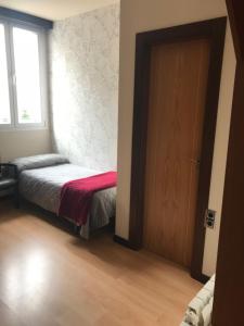 um pequeno quarto com uma cama e uma porta em Hostal de Cuenca em Cuenca
