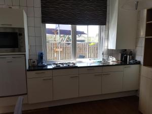 uma cozinha com armários brancos, uma janela e um lavatório em vakantiehuisje Cottage em Aagtekerke