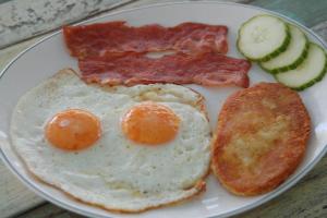 a plate with eggs bacon and toast and cucumbers at Hotel Paros in Parikia