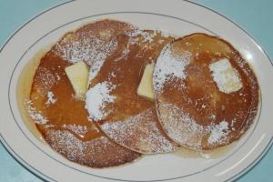 a plate of pancakes with powdered sugar and butter at Hotel Paros in Parikia